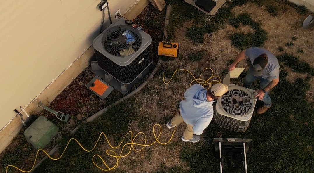 Two technicians repairing an air conditioner