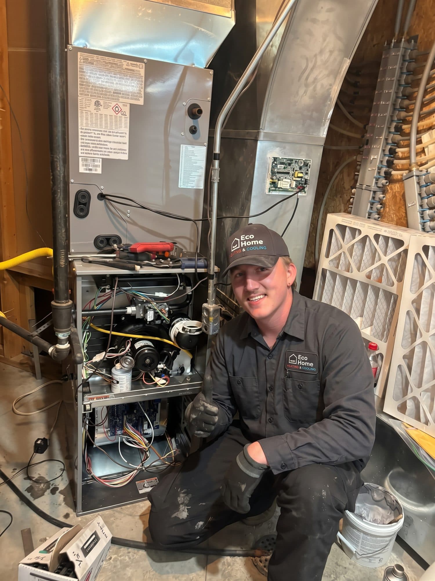 Eco Home technician in uniform next to a newly installed furnace