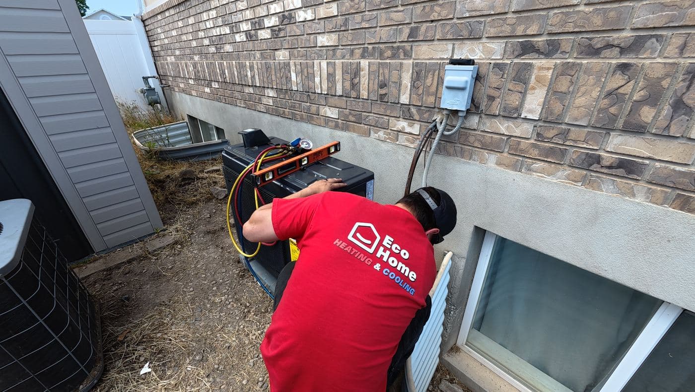 Eco Home technician leveling a new heat pump beside a Utah home