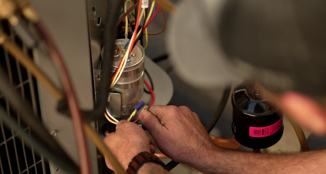 Eco Home technician servicing the electrical components of an outdoor unit during a maintenance visit