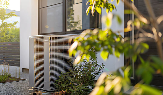 A white air conditioner positioned in front of a house, representing an efficient HVAC system for heating and cooling.